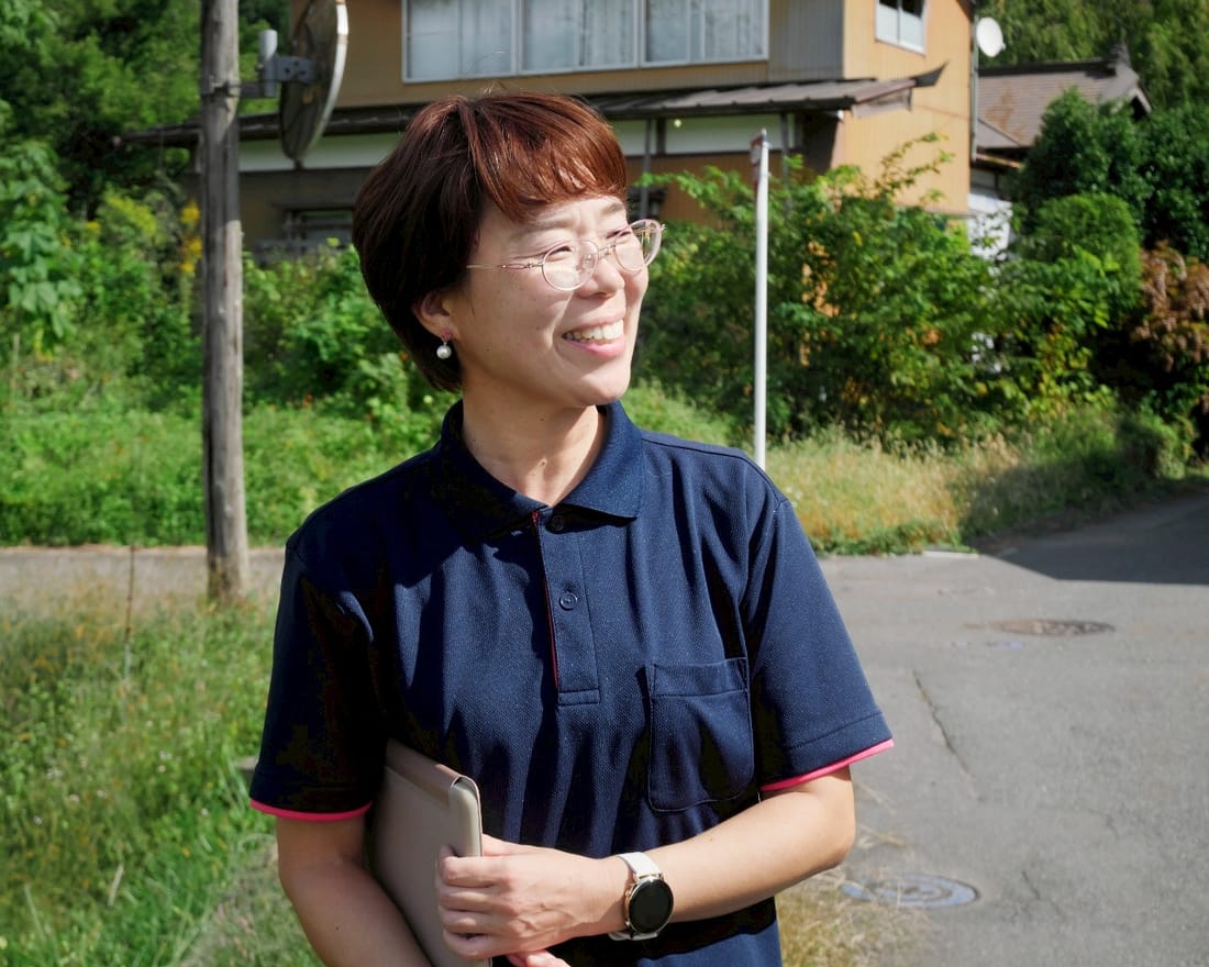 里山を背に、笑顔で立つ協同労働の担い手